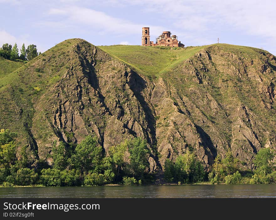 Under construction temple on high to river bank Yenisei