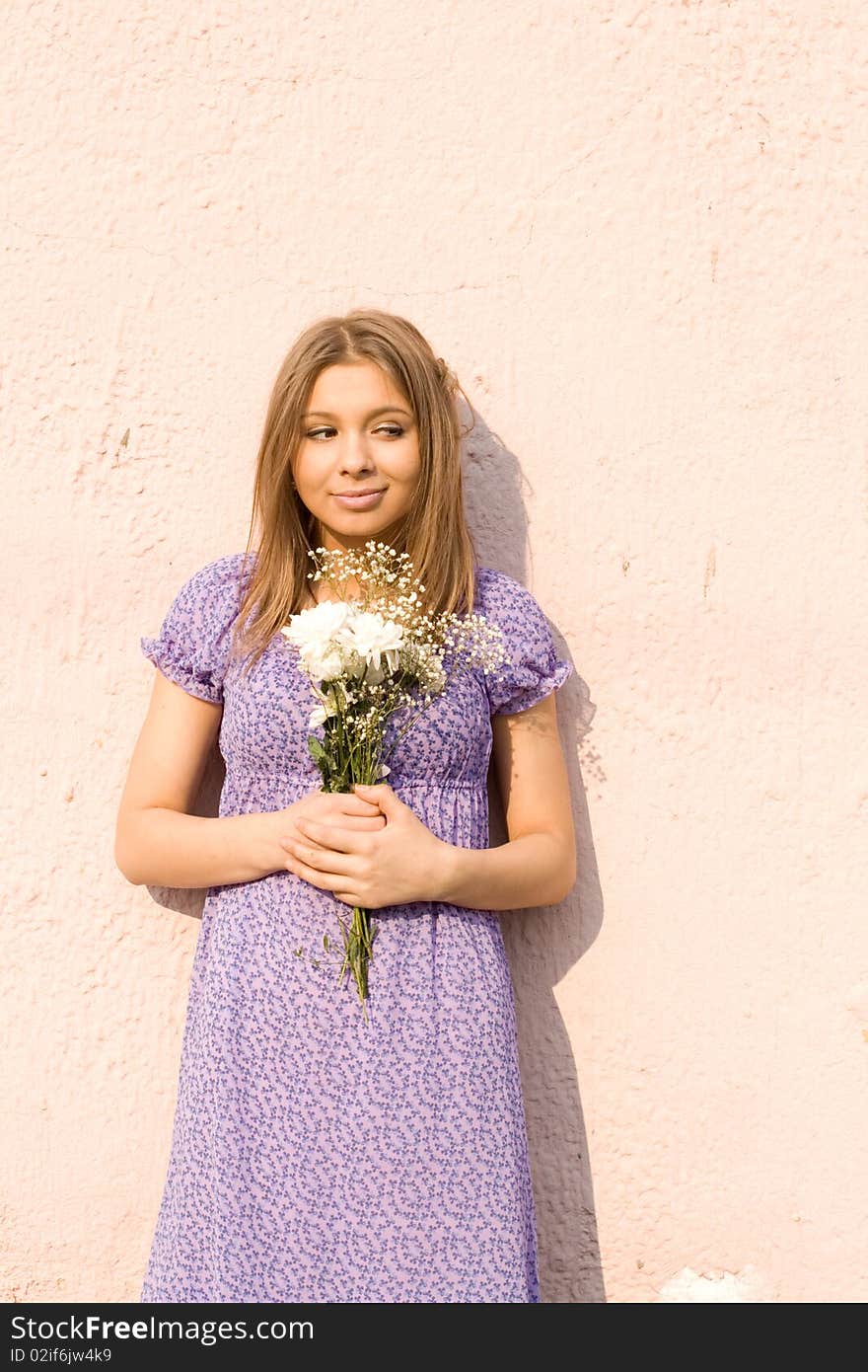 Girl with flowers standing outdoor near wall