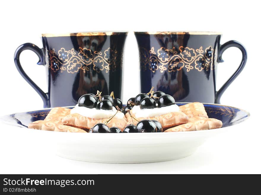 Dessert. Two cups of tea and cakes with black currant in sour cream. Isolated on white background. Dessert. Two cups of tea and cakes with black currant in sour cream. Isolated on white background