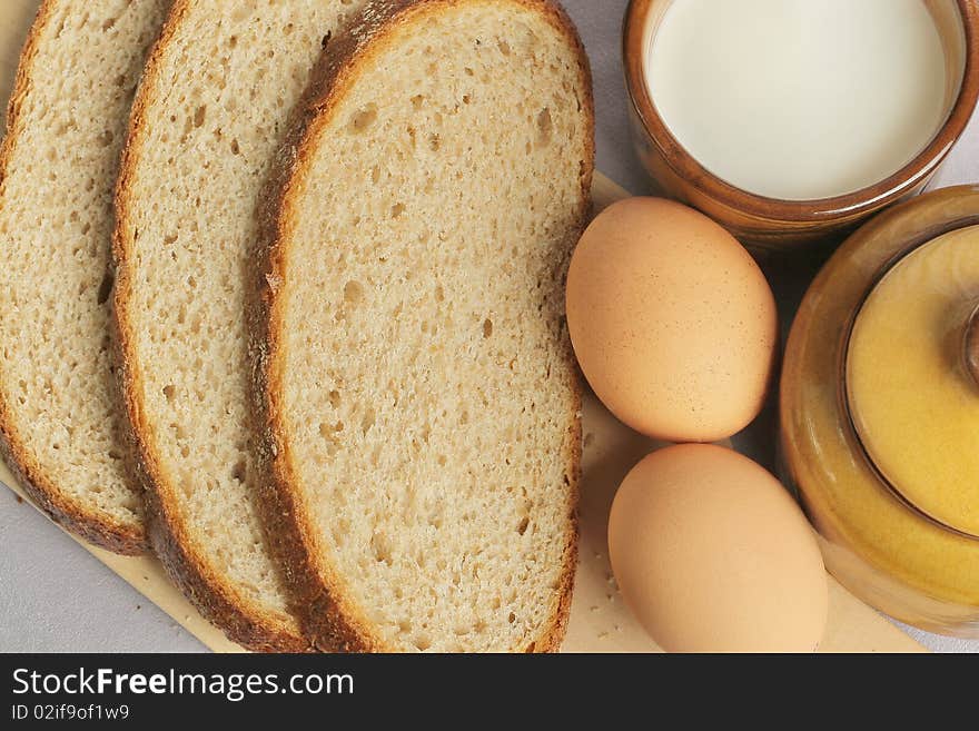 Breakfast. Eggs and a cup of milk. Slices of bread on wooden plate