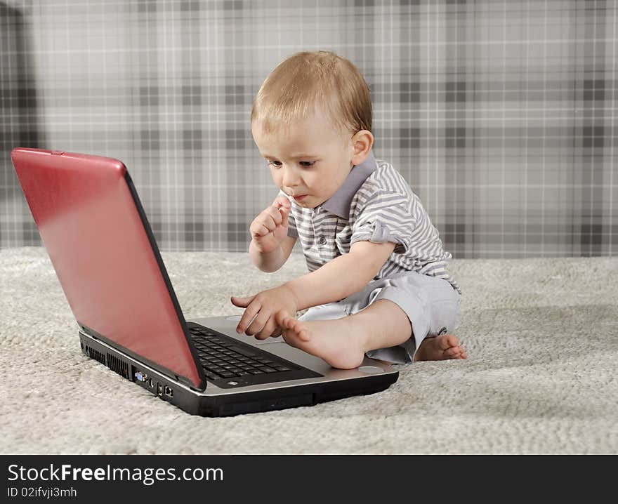 Boy playing with notebook and eating lollipop. Boy playing with notebook and eating lollipop