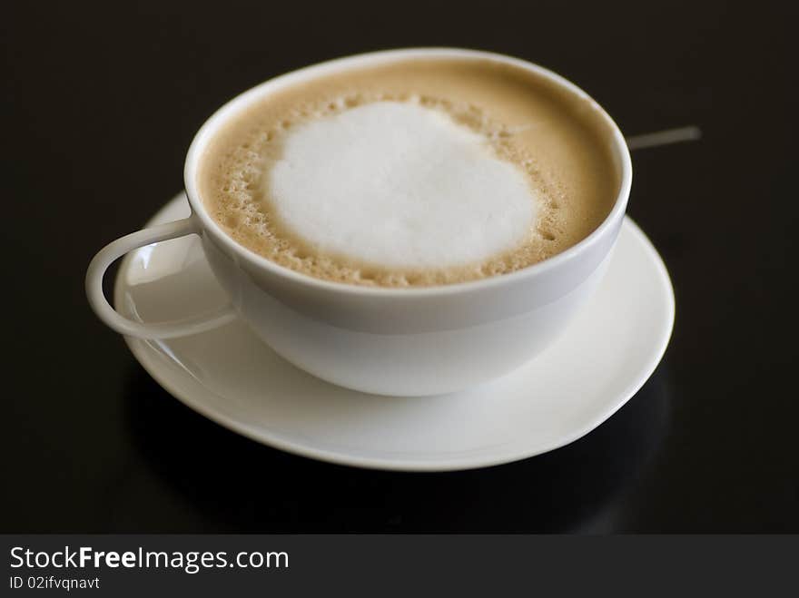 Cup of cappuccino coffee against black background. Cup of cappuccino coffee against black background