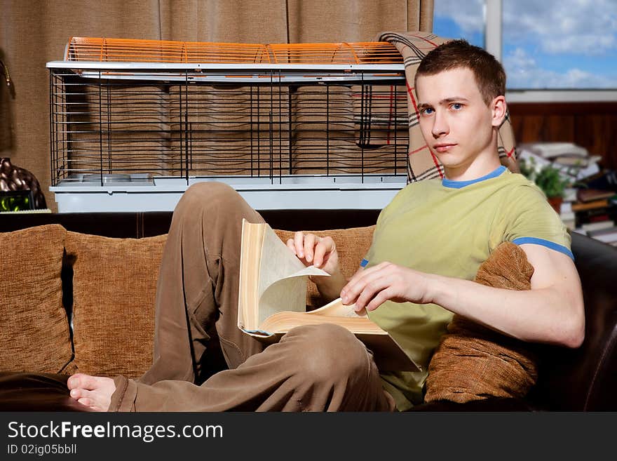 Handsome guy reading very thick book on his sofa. Handsome guy reading very thick book on his sofa