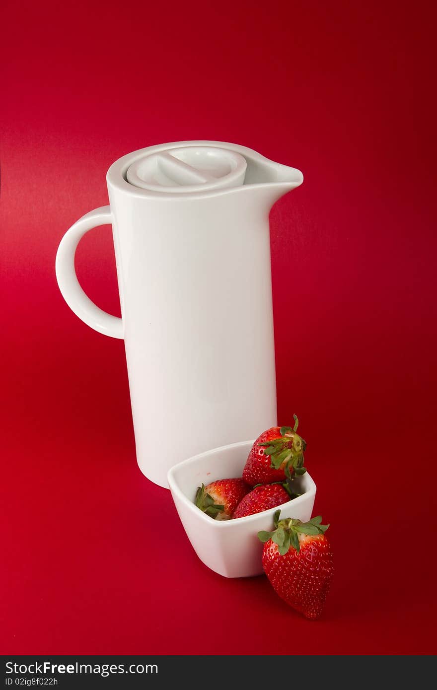 White jug with strawberry's on red background. White jug with strawberry's on red background