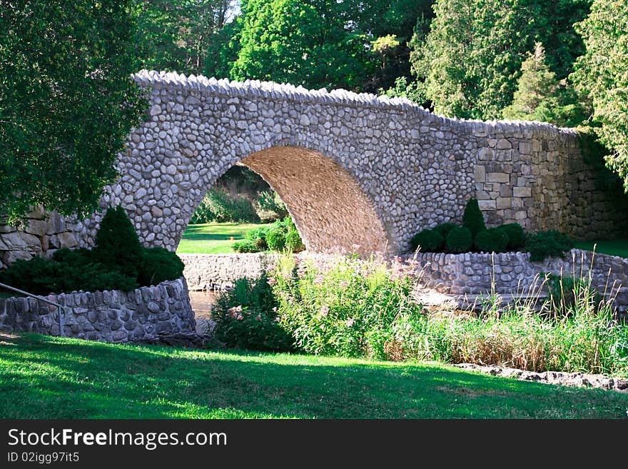 A stone bridge over a river in a fairy tale like park