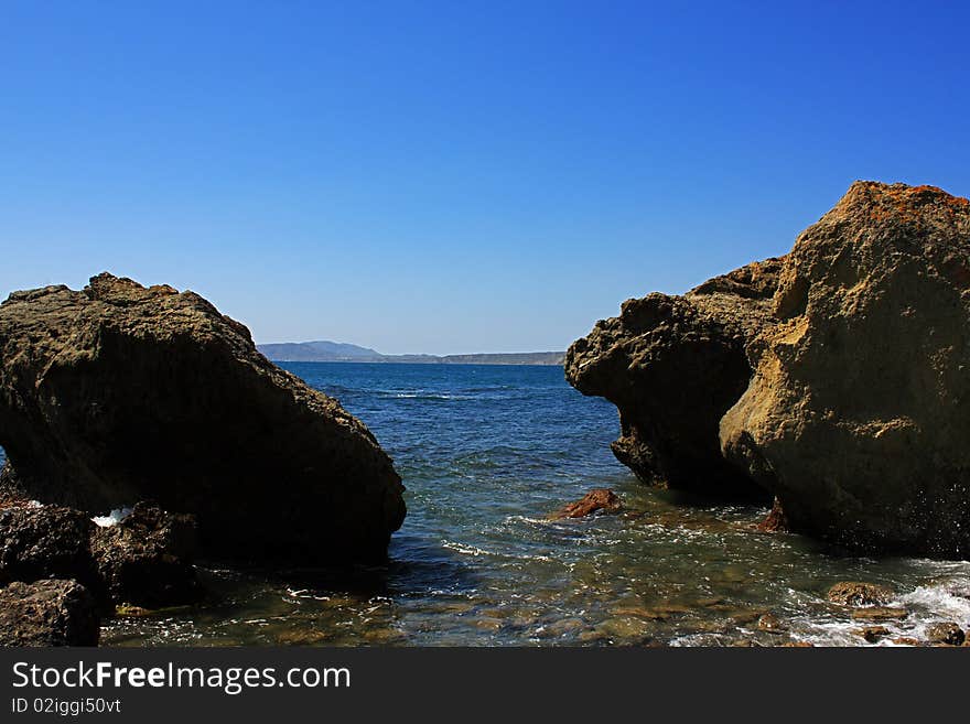 Seascape - a beautiful beach, sea and sky. In the foreground stones from the vent of an ancient volcano karadag. Seascape - a beautiful beach, sea and sky. In the foreground stones from the vent of an ancient volcano karadag