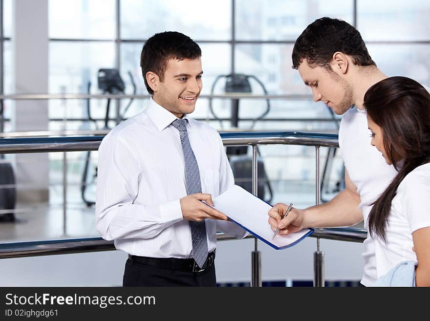 The young man signs the document in fitness club. The young man signs the document in fitness club