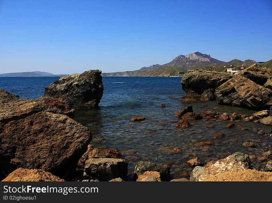 Seascape - a beautiful beach, sea and sky. In the foreground stones from the vent of an ancient volcano karadag. Seascape - a beautiful beach, sea and sky. In the foreground stones from the vent of an ancient volcano karadag