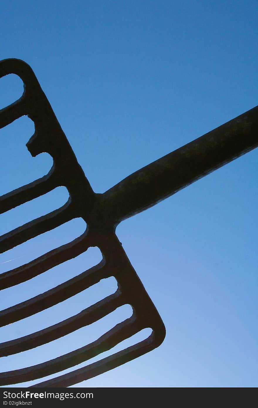 Hay bailling fork made from steel as a artistic item, its balanced center point  shot against the blue sky. Hay bailling fork made from steel as a artistic item, its balanced center point  shot against the blue sky.