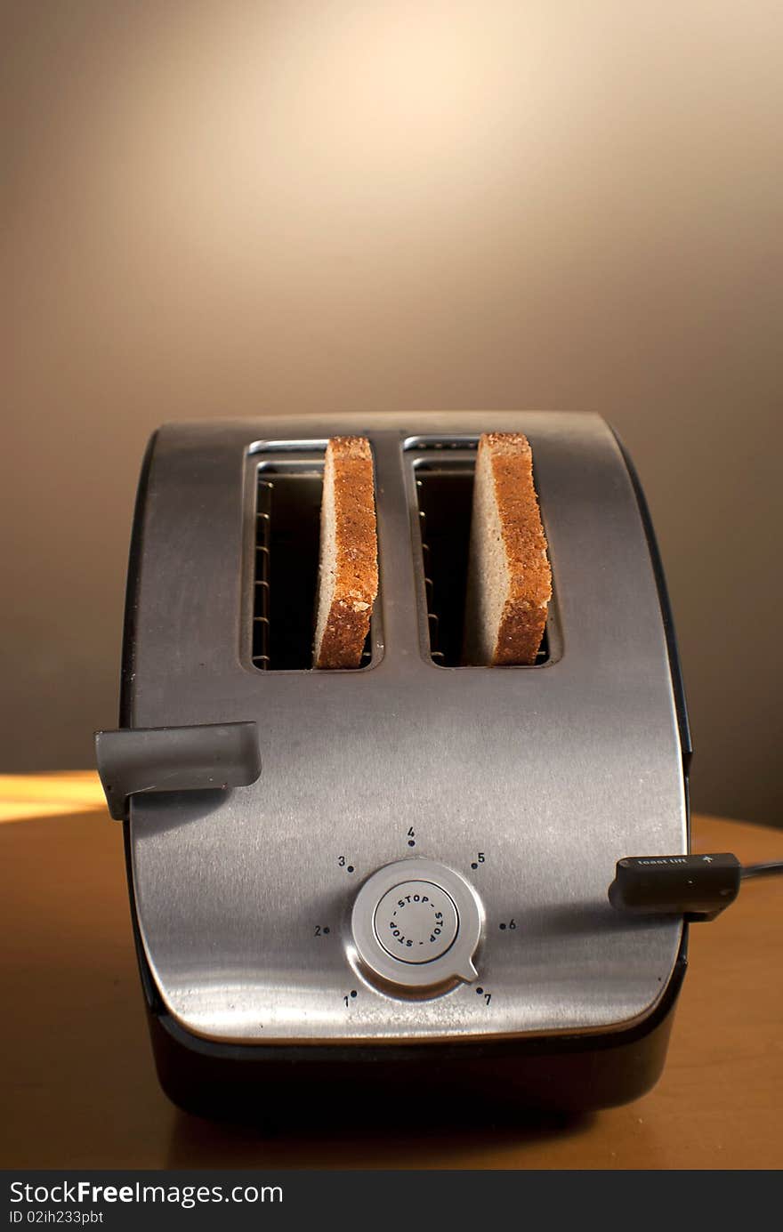 A toaster with two pieces of bread on a table. A toaster with two pieces of bread on a table.