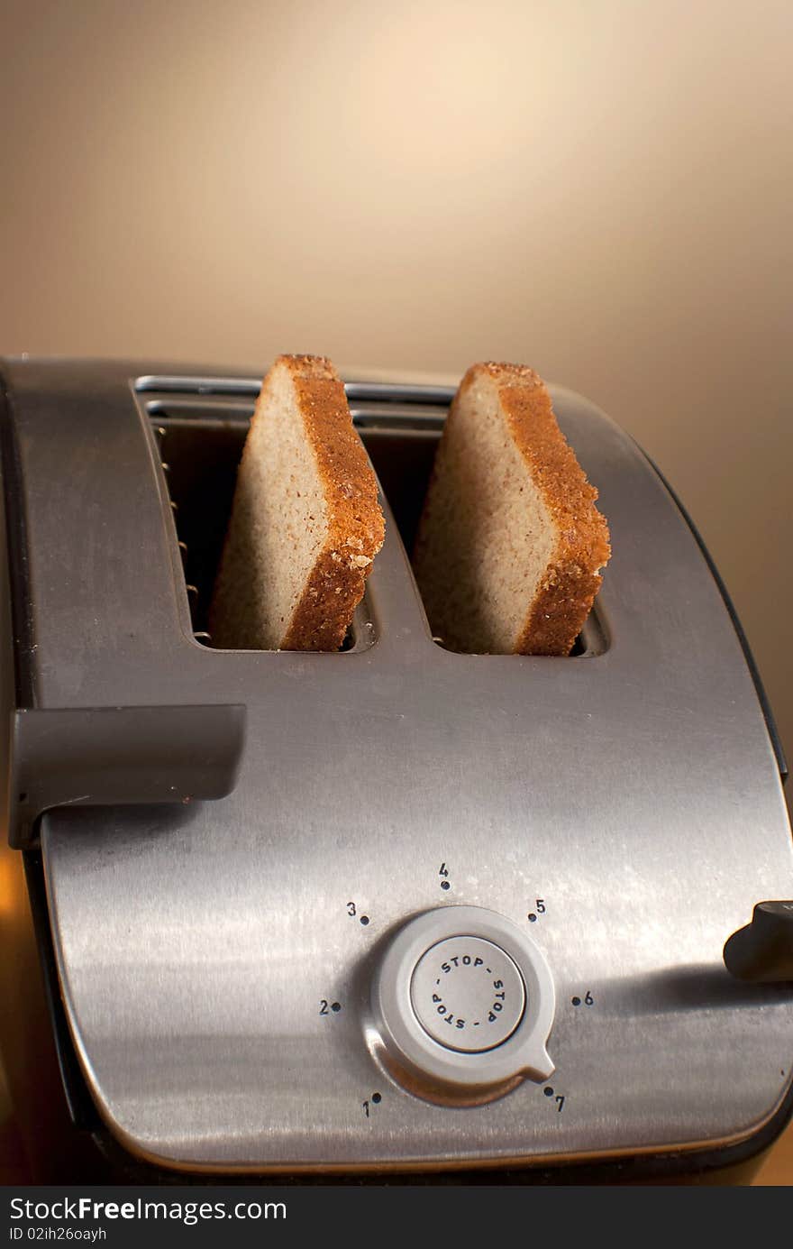 Two pieces of wheat bread sit in a toaster. Two pieces of wheat bread sit in a toaster.