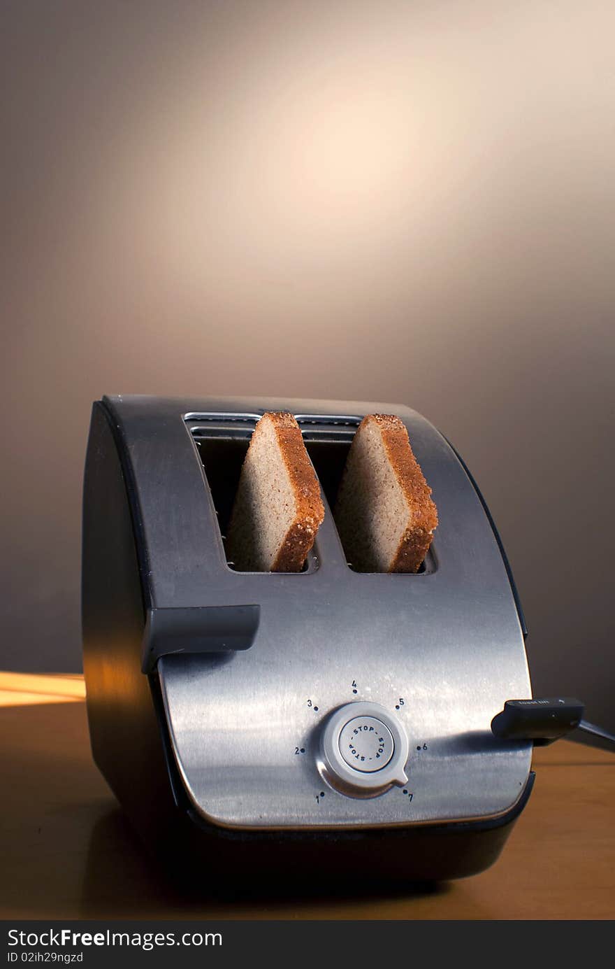 A toaster with two pieces of bread sits on a table. A toaster with two pieces of bread sits on a table.