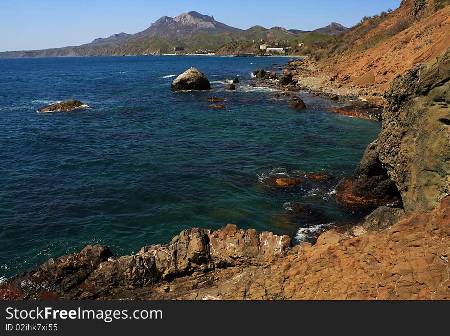 Seascape - a beautiful beach, sea and sky. In the foreground stones from the vent of an ancient volcano karadag. Seascape - a beautiful beach, sea and sky. In the foreground stones from the vent of an ancient volcano karadag