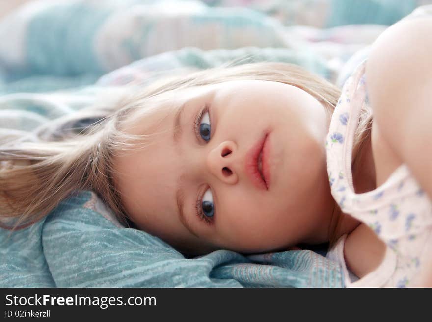 Beautiful little girl in the morning lying in bed