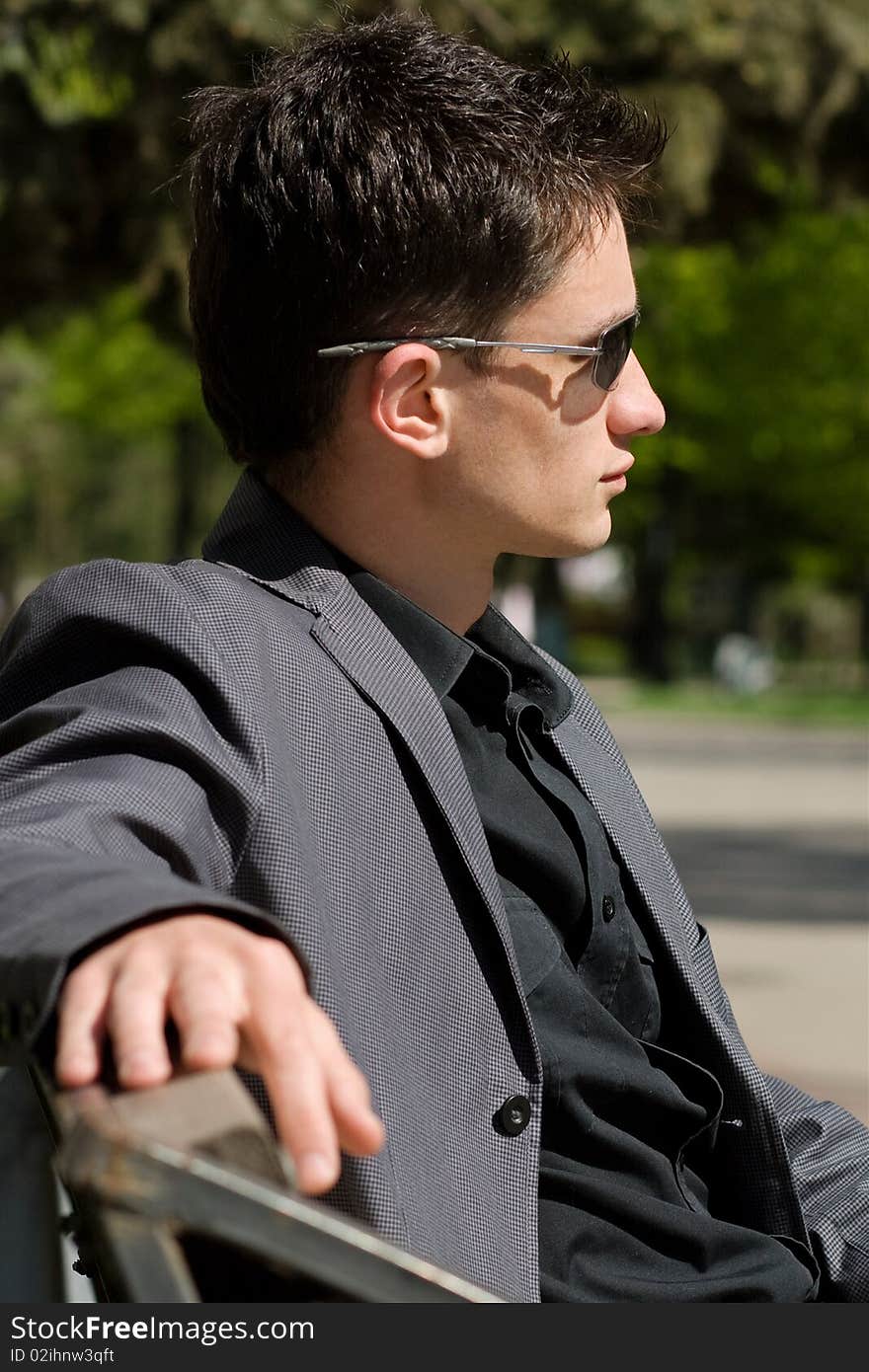 Young businessman sitting on a bench in the middle of a day. Young businessman sitting on a bench in the middle of a day