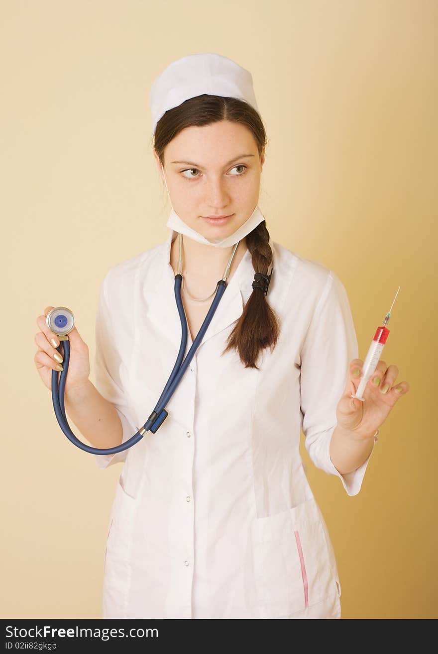 Portrait of young nurse or doctor with surgical face mask, syringe and stethoscope, studio background. Portrait of young nurse or doctor with surgical face mask, syringe and stethoscope, studio background.