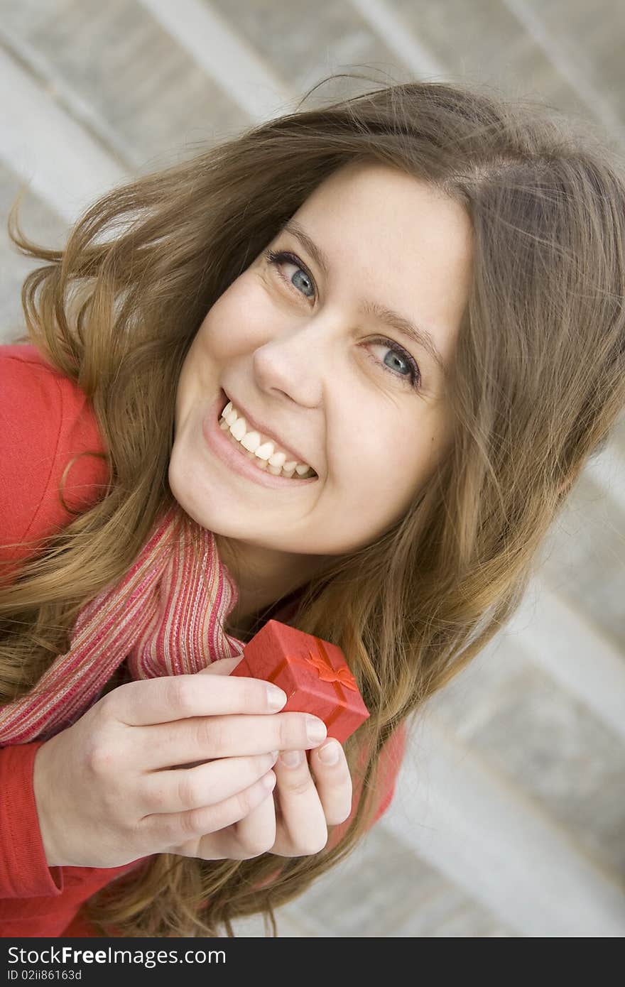 Young woman sitting on the stairs to the street, and holds a red gift box. Young woman sitting on the stairs to the street, and holds a red gift box