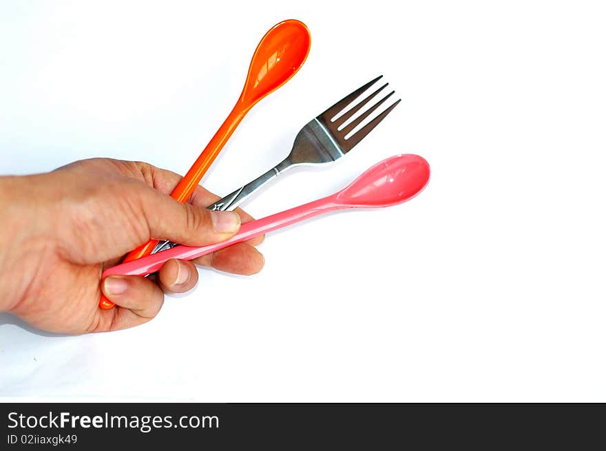 A pair of colorful plastic spoons with a stainless steel fork in hand isolated on white background. A pair of colorful plastic spoons with a stainless steel fork in hand isolated on white background