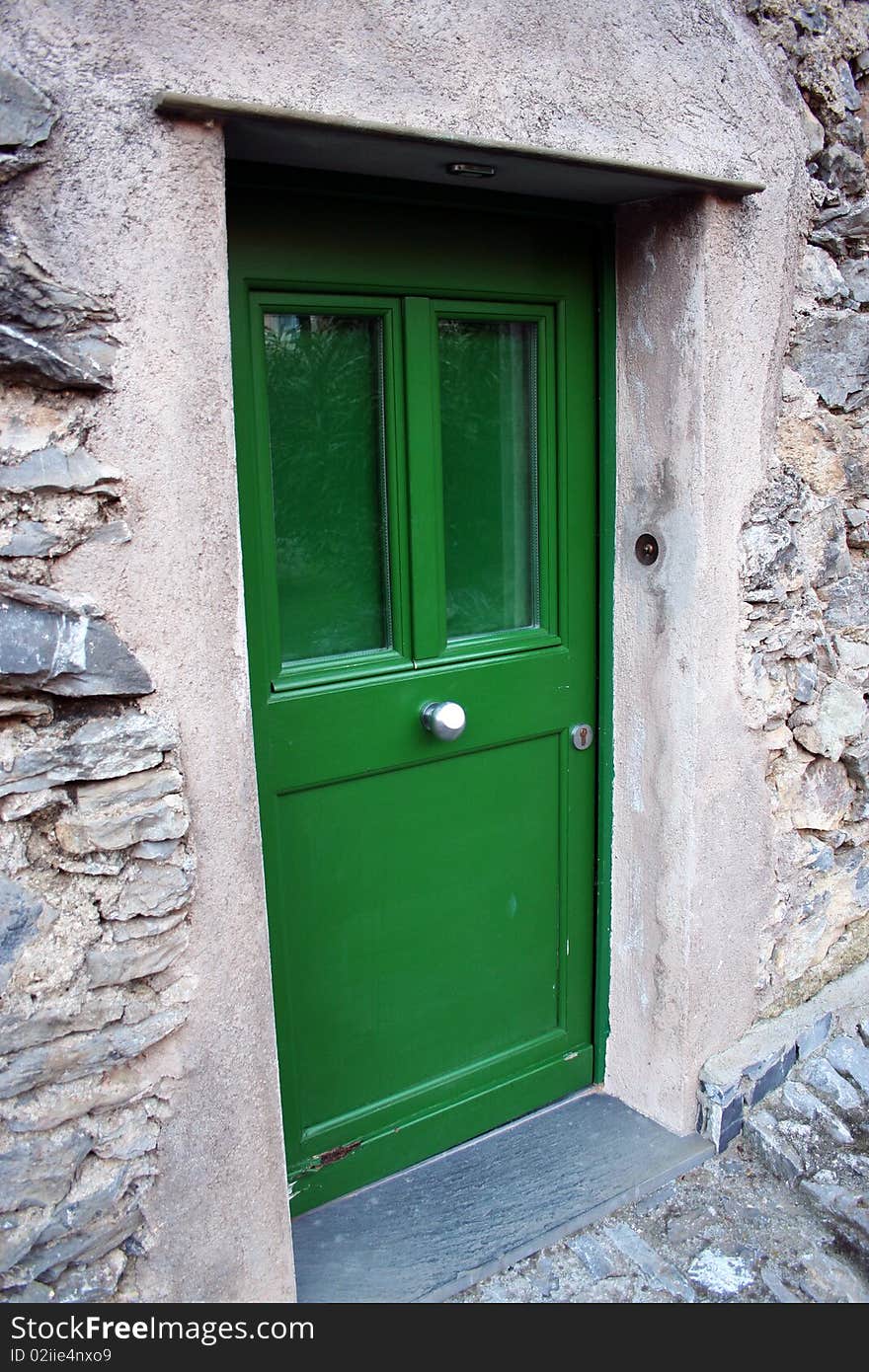 Detail of a green door in a restorated stone house in one italian country village