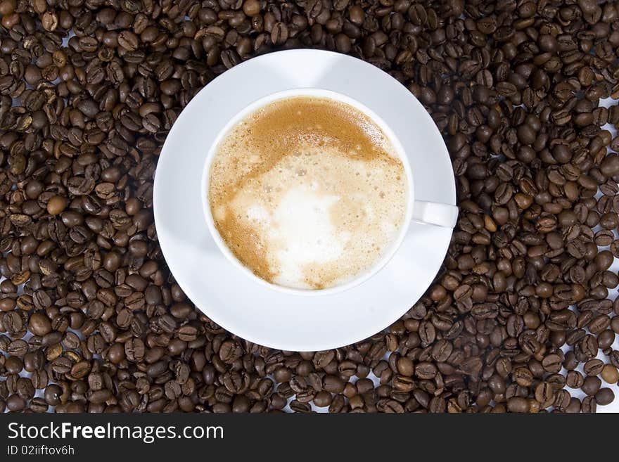 Cup of coffee sitting in a bed of coffee beans