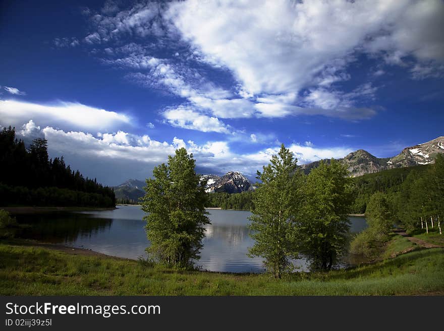 Mountain lake in the Spring with clouds with snow covered mountains reflected in the lake