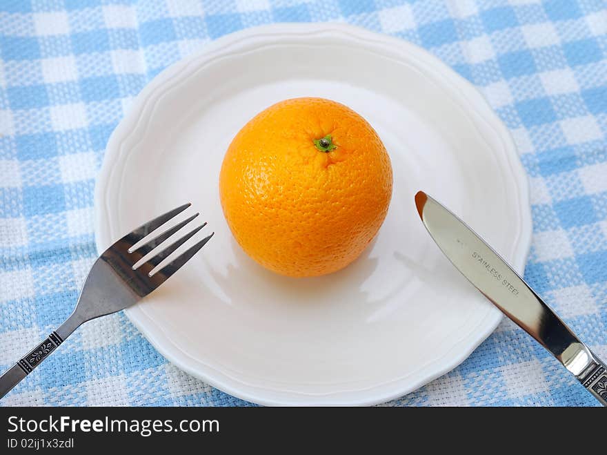 Fork and knife ready to eat orange on plate. Healthy eating and lifestyle, diet and nutrition, and fresh fruit concepts . Fork and knife ready to eat orange on plate. Healthy eating and lifestyle, diet and nutrition, and fresh fruit concepts .