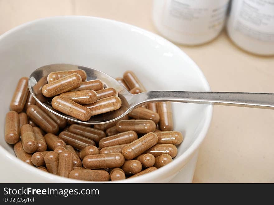 Spoonful of medicine capsules in soup bowl. Signifying drug addiction, healthy eating and lifestyle, dieting and slimming, and healthcare concepts.