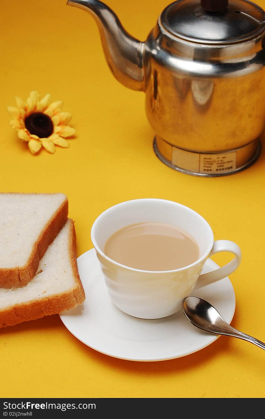 A cup of milky tea with bread and pot