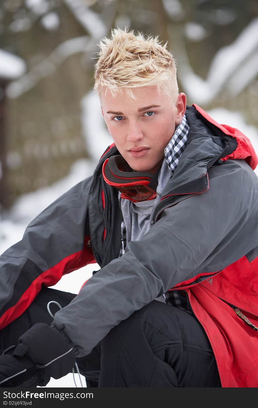 Teenage Boy Wearing Winter Clothes In Snowy Landscape Looking At Camera