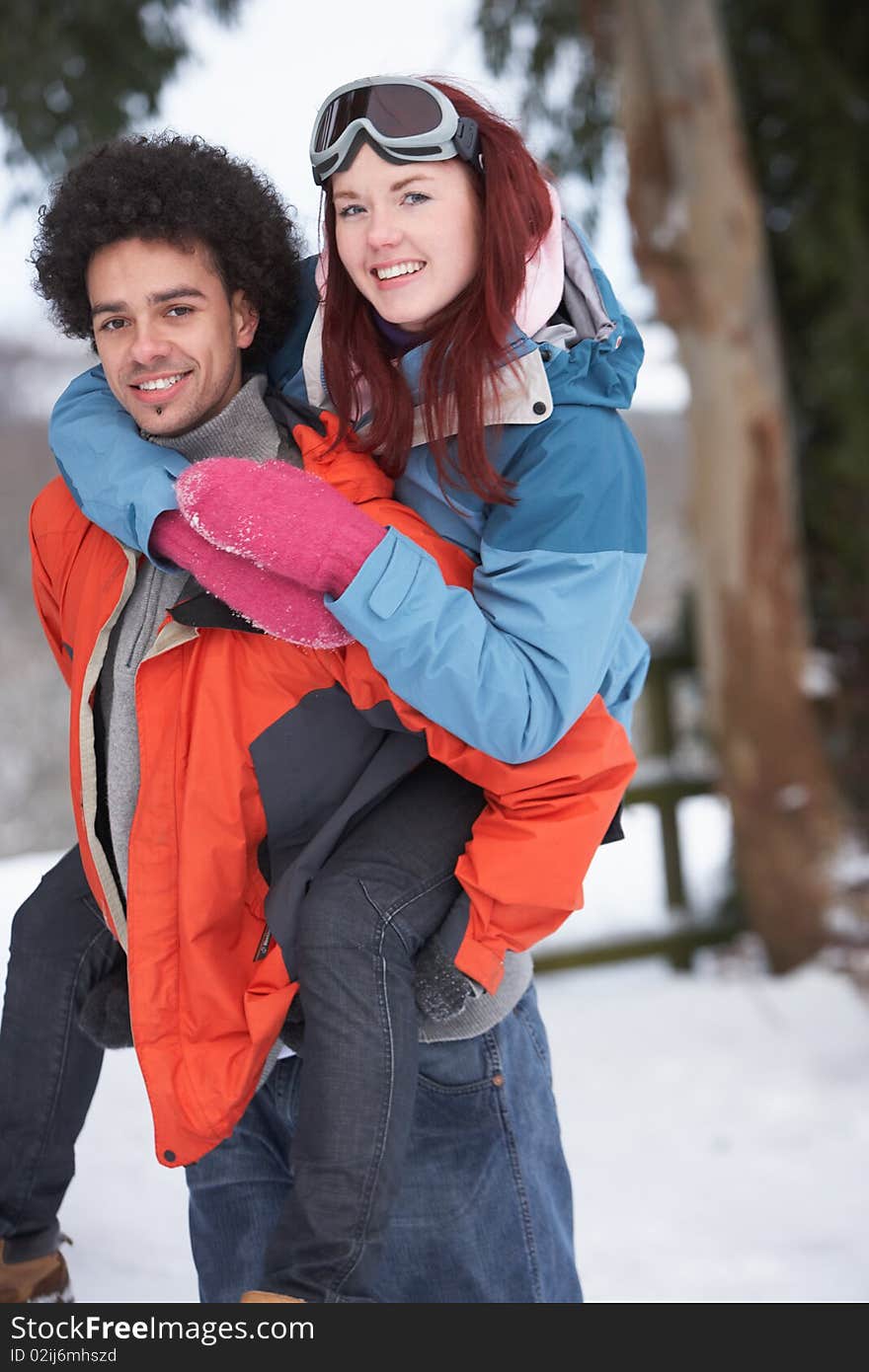 Teenage Boy Giving Girl Piggyback In Snowy Landscape