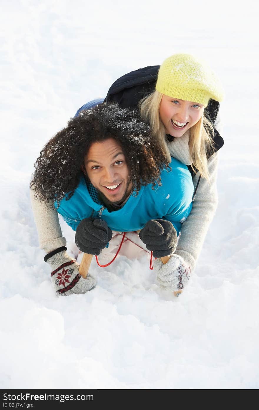 Couple Sledging Through Snowy Woodland