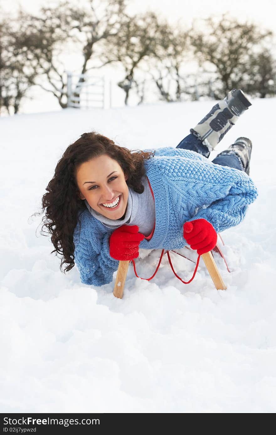 Young Woman Riding On Sledge In Snowy Landscape