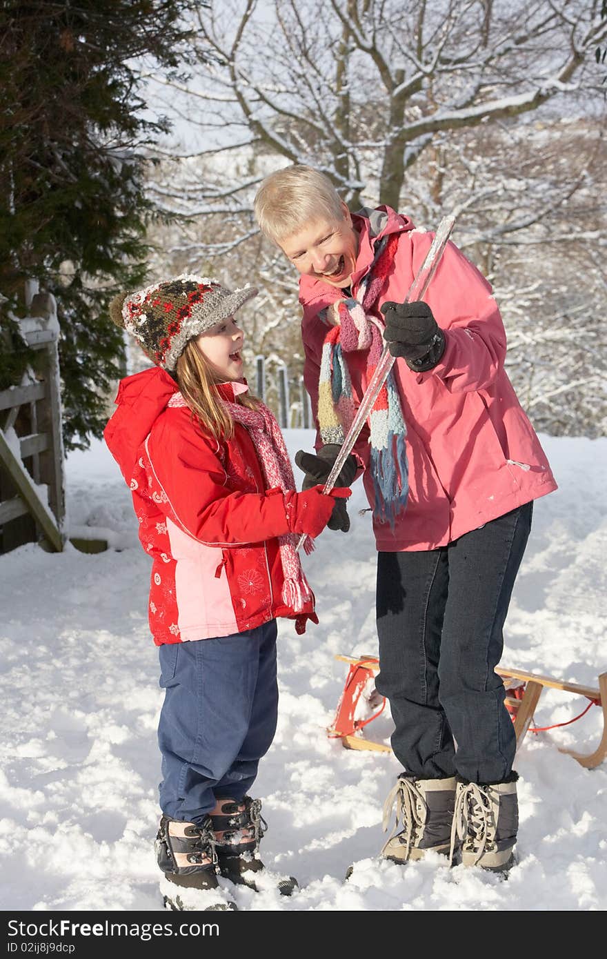Young Girl Showing Grandmother Icicle In Snowy Landscape Having Fun
