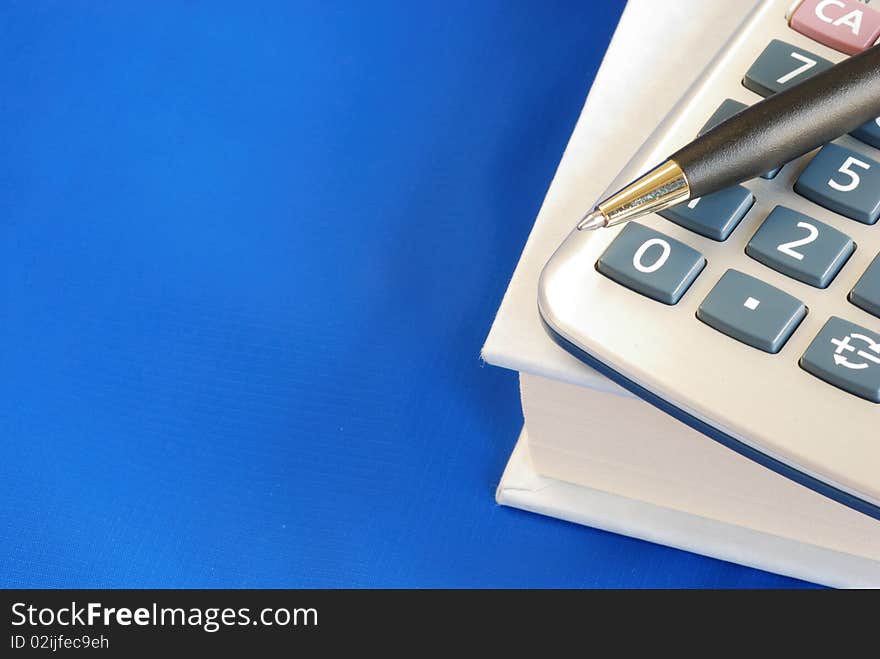 Pen and calculator on the book isolated on blue concepts education and knowledge