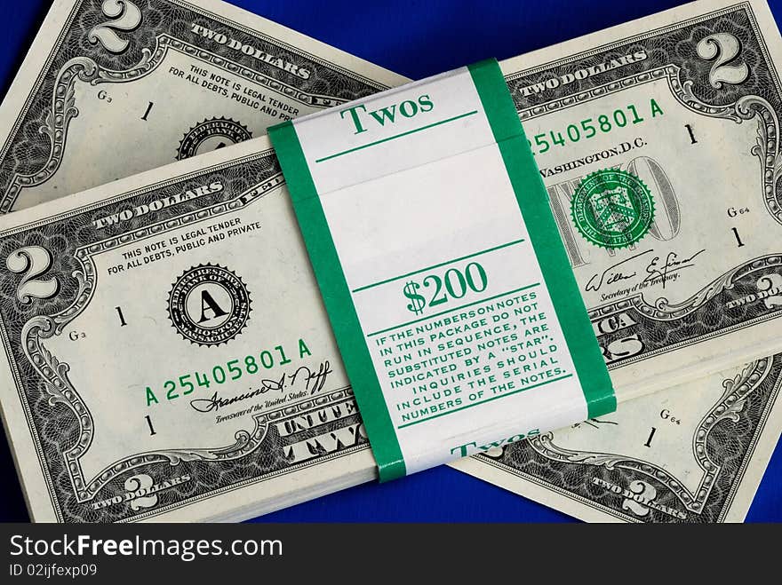 Piles of United States two dollar bills isolated on blue