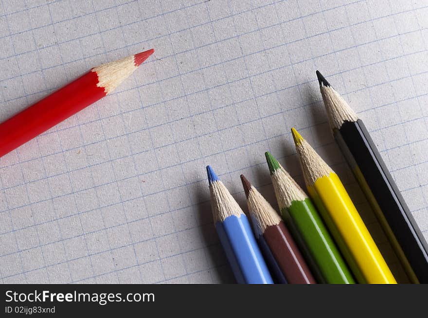 Colorful pencils set macro shot over checked paper background