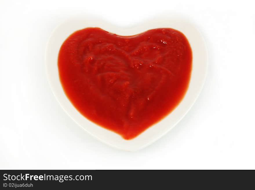 Tomato sauce in the form of heart on a white background