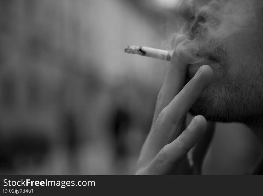 A young man while smiking a cigarette. A young man while smiking a cigarette