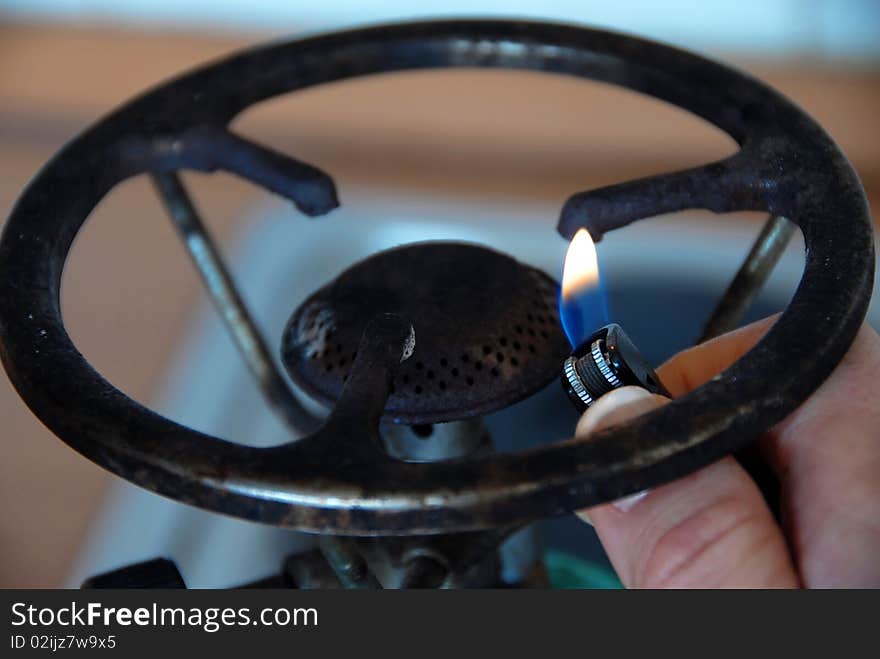 Hand with lighter by gas hotplate closeup. Hand with lighter by gas hotplate closeup