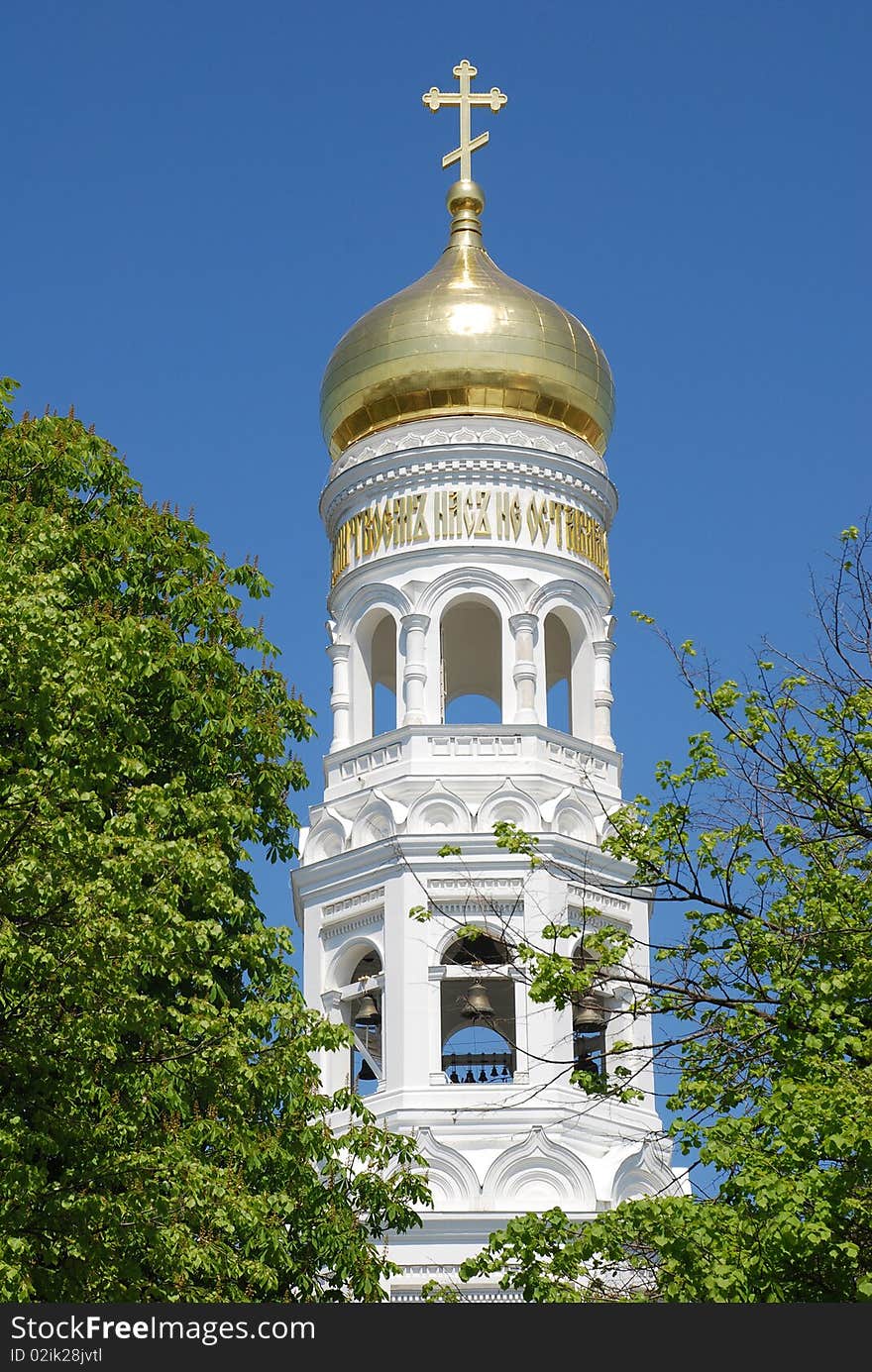 Beautiful russian orthodox cathedral with gold dome and white bell tower on blue sky background. Beautiful russian orthodox cathedral with gold dome and white bell tower on blue sky background.