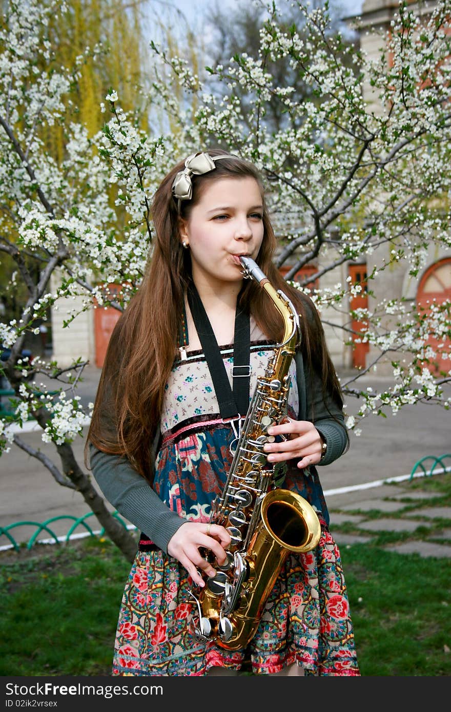 Beautiful smiling girl with saxophone, spring tree. Beautiful smiling girl with saxophone, spring tree