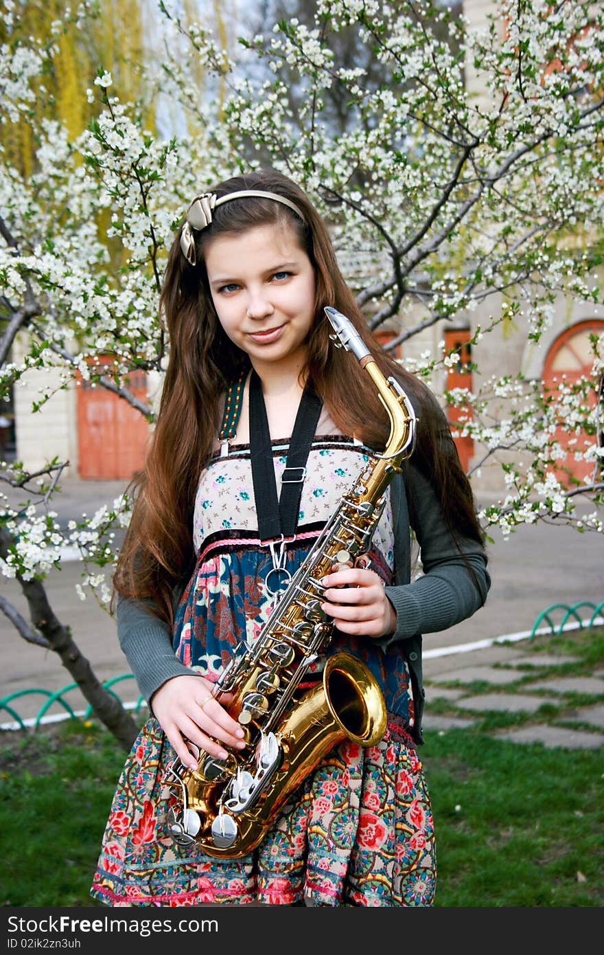 Beautiful smiling girl with saxophone, spring tree. Beautiful smiling girl with saxophone, spring tree