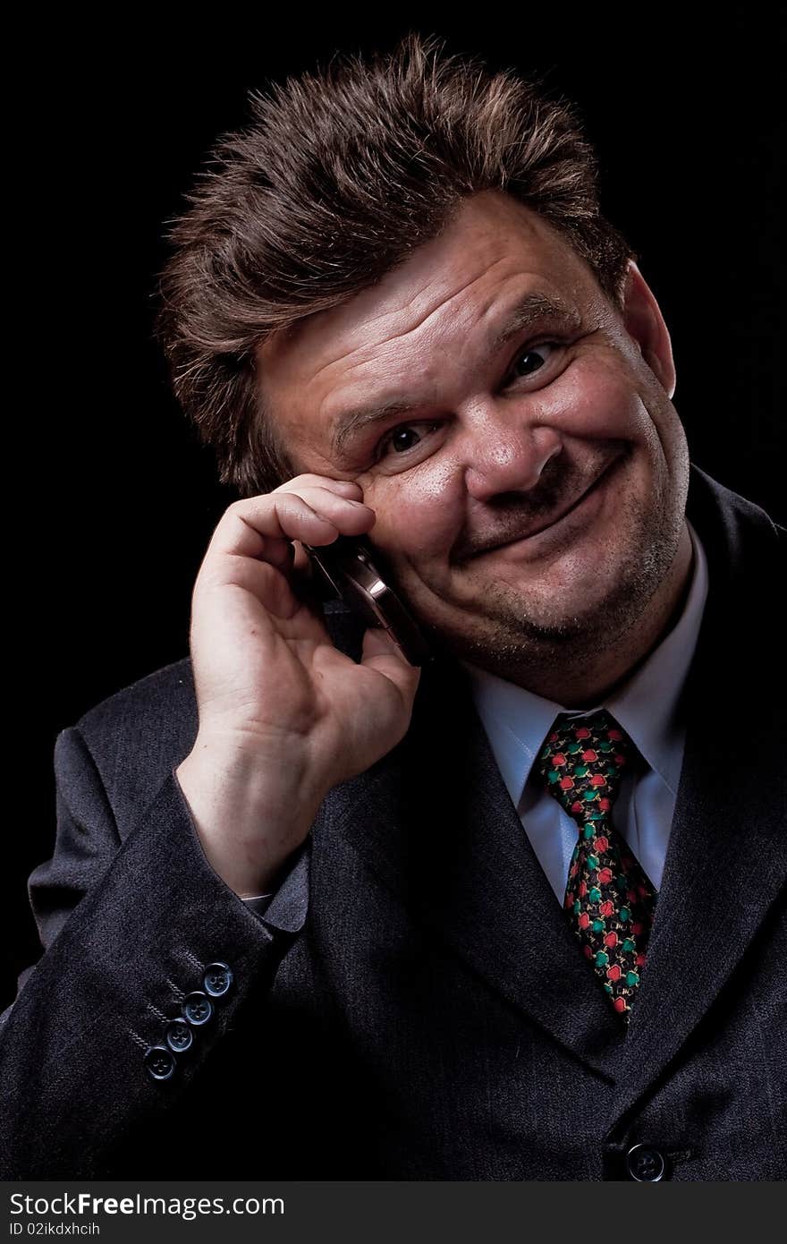 Businessman with mobile phone speaking on black background