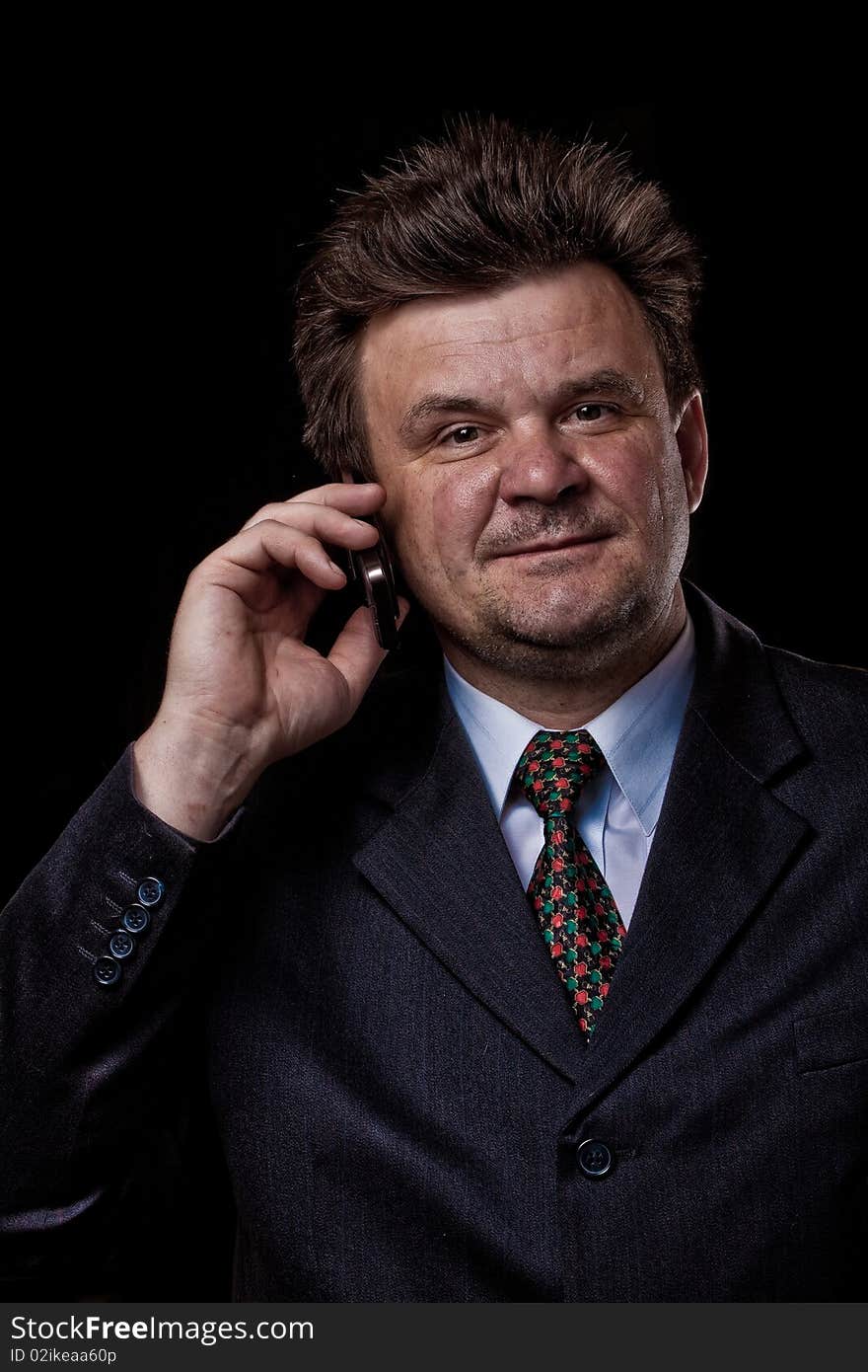 Businessman with mobile phone speaking on black background