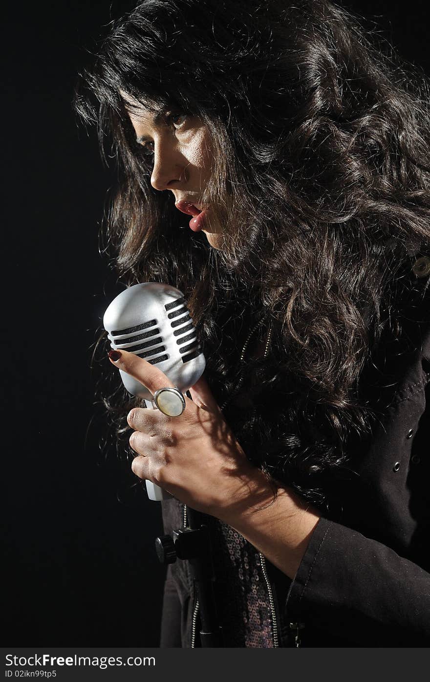 Portrait of young beautiful brunette woman singing with retro microphone - isolated on black. Portrait of young beautiful brunette woman singing with retro microphone - isolated on black