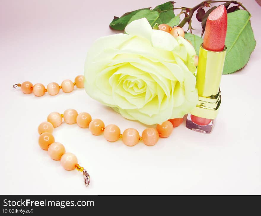 Pink lipstick in gold box with white rose on background. Pink lipstick in gold box with white rose on background