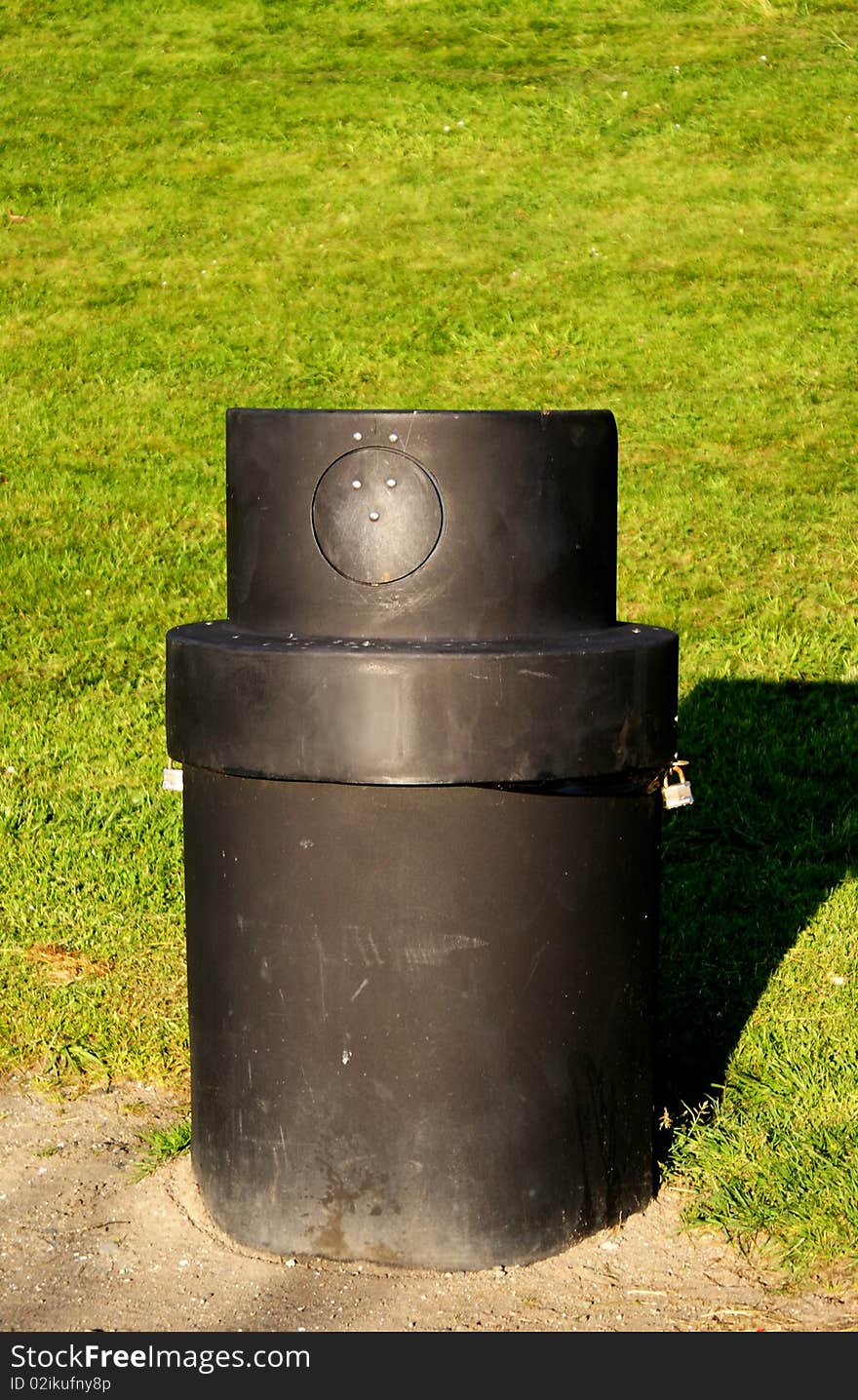 A black litter bin in a park