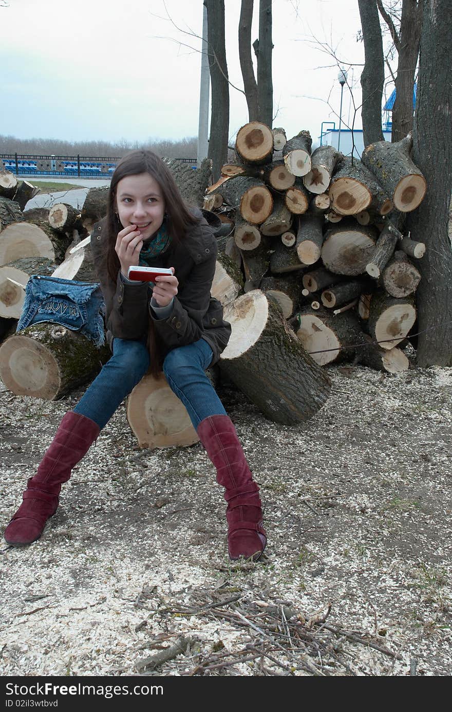 Girl sitting on logs with a mobile phone