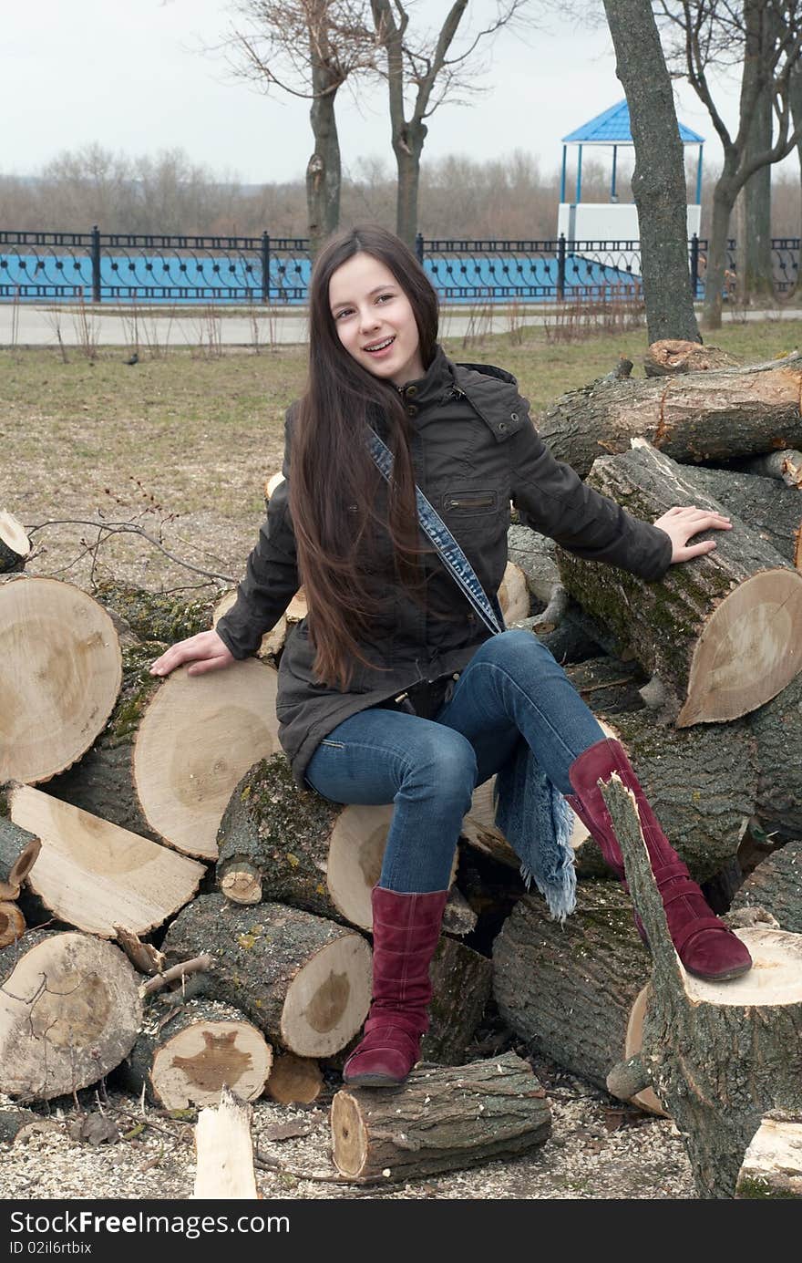 Young beautiful girl sitting on logs. Young beautiful girl sitting on logs