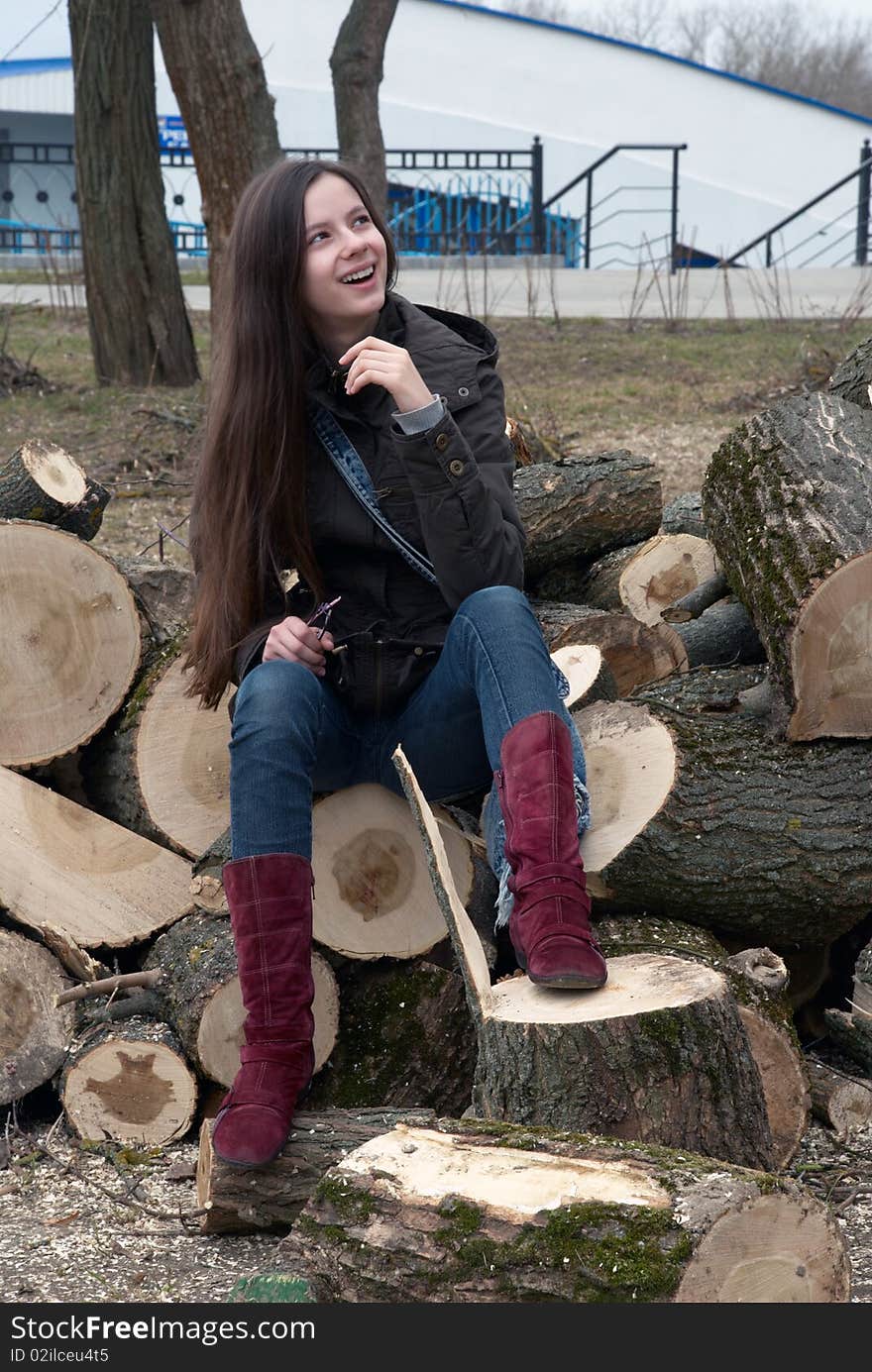 Young beautiful teenage girl sitting on logs